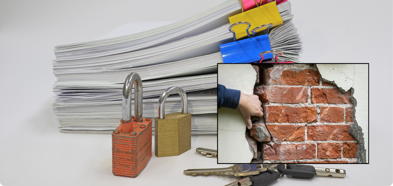 Ein Stapel Papiere mit mehreren Vorhängeschlössern und einer Hand, die einen Mauerbrocken hebt.