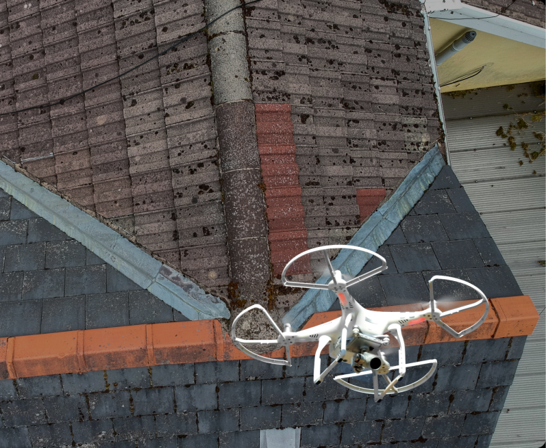 Ein Drohne schwebt über einem Dach mit Ziegeln und Holzverkleidung.